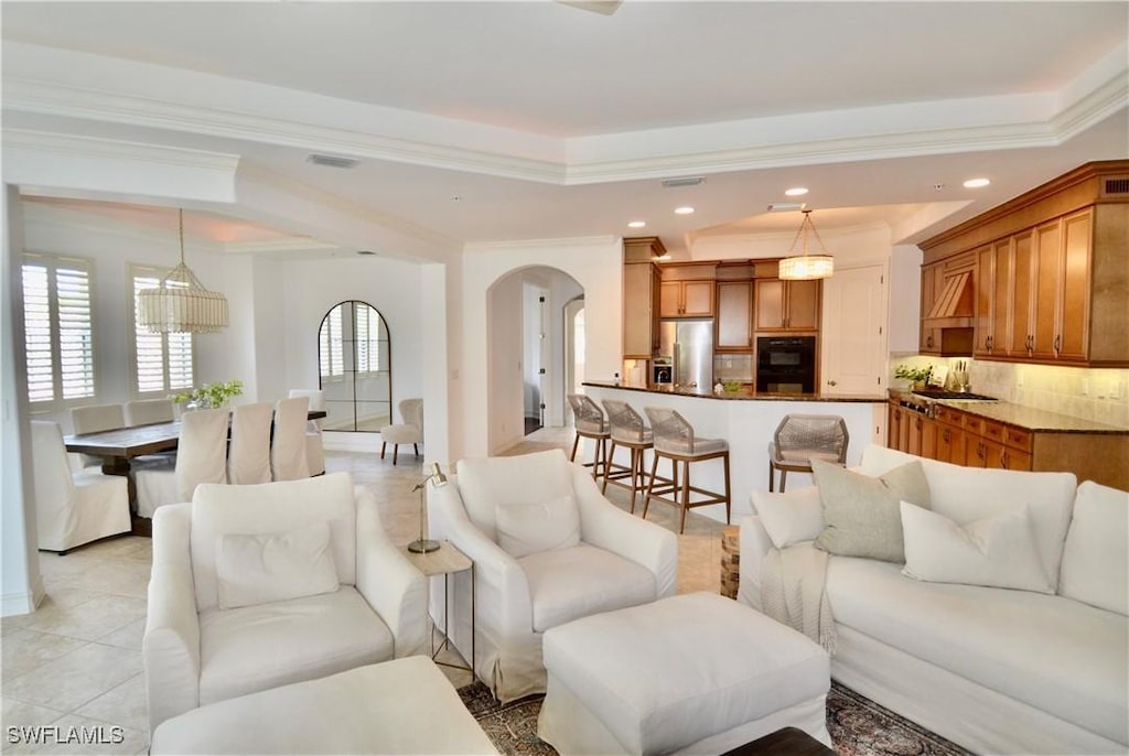 living room featuring arched walkways, light tile patterned floors, recessed lighting, and a raised ceiling