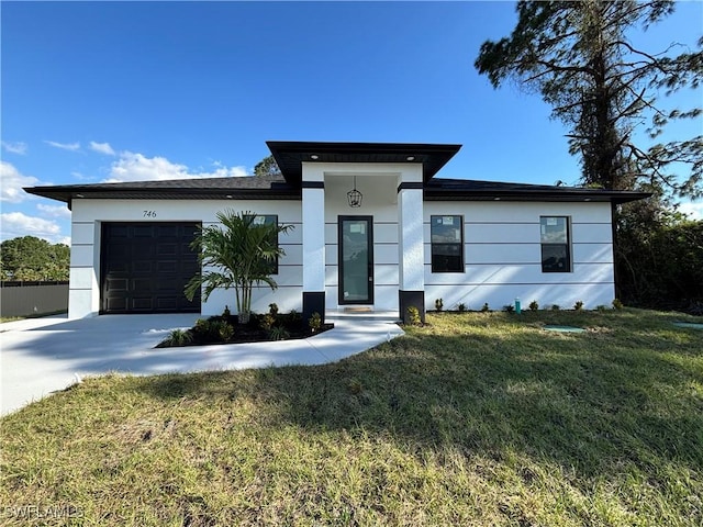 view of front of property featuring stucco siding, concrete driveway, a garage, and a front yard