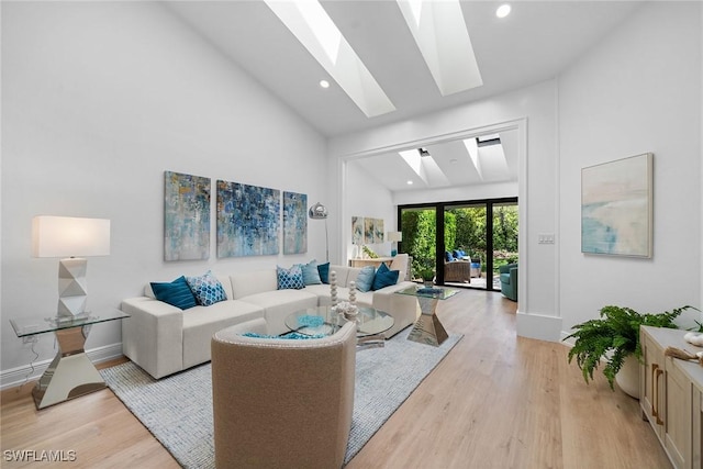 living area with light wood-type flooring, high vaulted ceiling, recessed lighting, a skylight, and baseboards