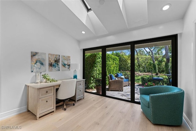 home office with vaulted ceiling with skylight, plenty of natural light, baseboards, and light wood-type flooring