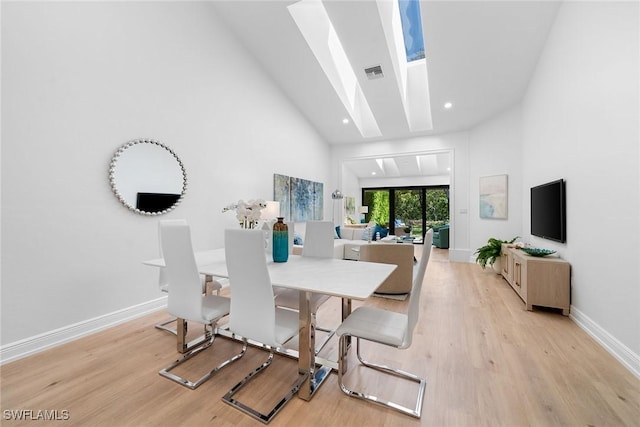 dining room with baseboards, visible vents, a skylight, and light wood-style floors