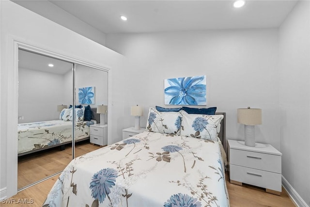 bedroom featuring light wood finished floors, recessed lighting, baseboards, and a closet