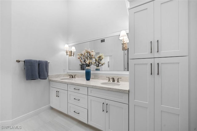 bathroom with double vanity, baseboards, visible vents, and a sink