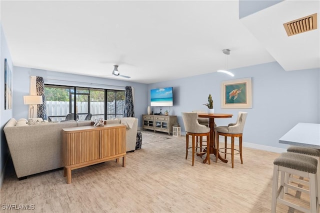 living area with visible vents, baseboards, a ceiling fan, and light wood finished floors