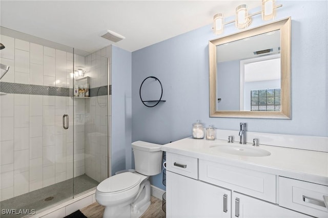 bathroom featuring visible vents, toilet, a stall shower, wood finished floors, and vanity