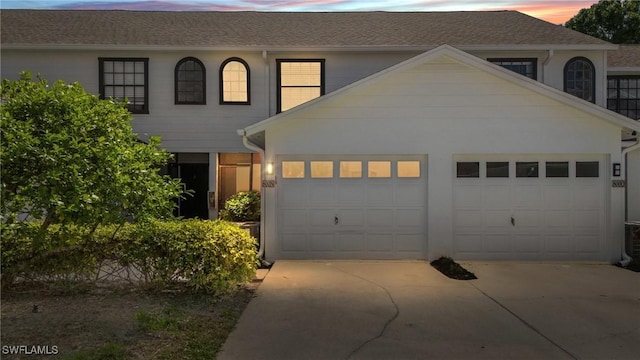 view of front of home featuring roof with shingles, concrete driveway, and an attached garage