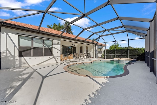view of pool featuring glass enclosure, a patio, a ceiling fan, and a pool with connected hot tub