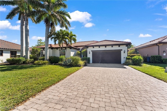 mediterranean / spanish home with an attached garage, stucco siding, a front lawn, a tile roof, and decorative driveway