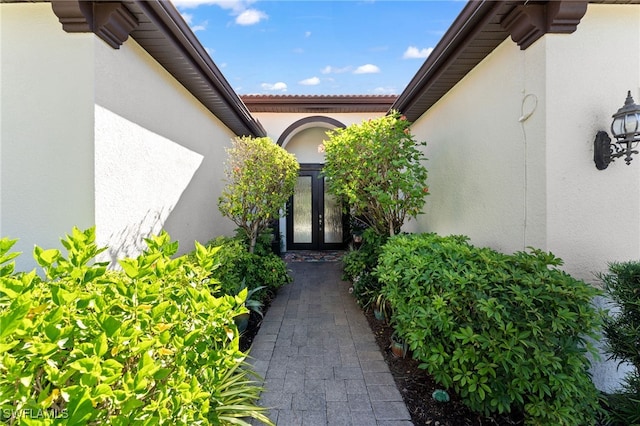 view of exterior entry featuring stucco siding and french doors