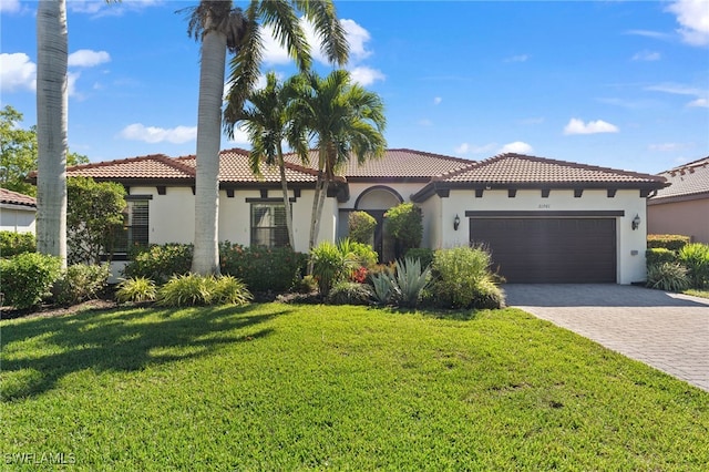 mediterranean / spanish-style house featuring a garage, decorative driveway, stucco siding, and a tile roof