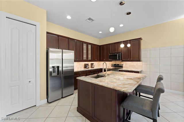 kitchen featuring visible vents, light stone countertops, dark brown cabinetry, appliances with stainless steel finishes, and a sink