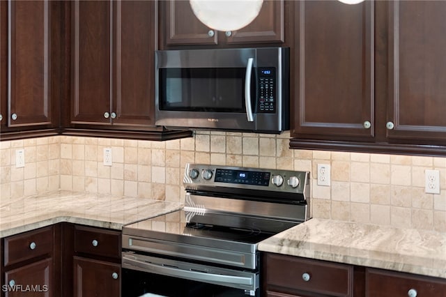 kitchen with decorative backsplash, dark brown cabinets, light stone countertops, and stainless steel appliances