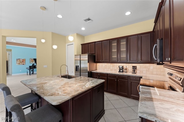kitchen featuring visible vents, light tile patterned floors, appliances with stainless steel finishes, a kitchen breakfast bar, and a sink