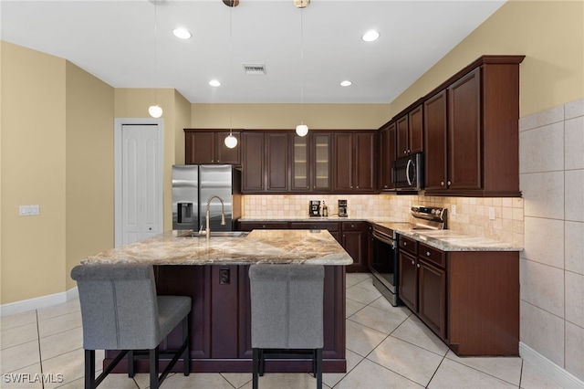kitchen featuring visible vents, light stone counters, decorative light fixtures, stainless steel appliances, and dark brown cabinets