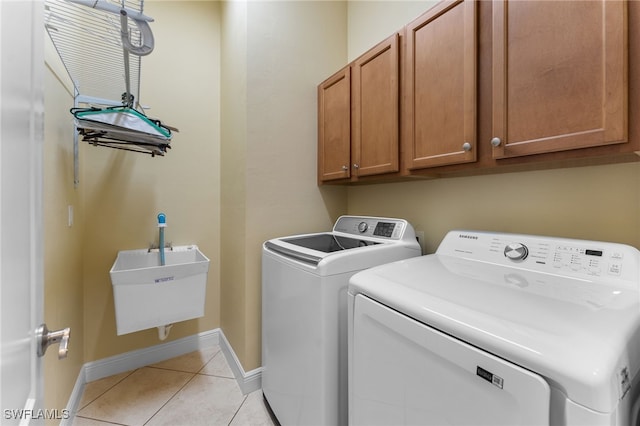 laundry room with a sink, cabinet space, separate washer and dryer, light tile patterned floors, and baseboards