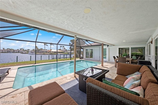 pool with an outdoor living space, glass enclosure, a water view, and a patio area