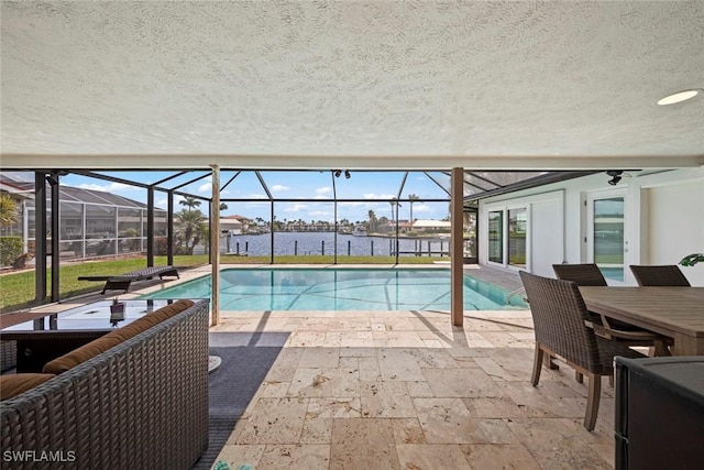 outdoor pool featuring glass enclosure, a water view, outdoor dining space, and a patio area