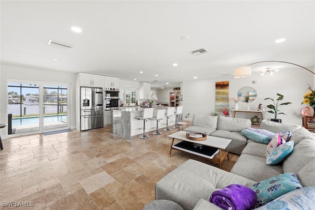 living area featuring stone tile floors, visible vents, and recessed lighting