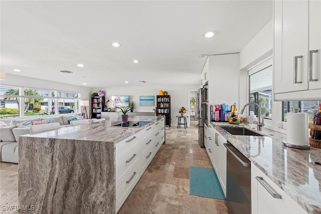 kitchen with open floor plan, white cabinets, stainless steel appliances, and a sink