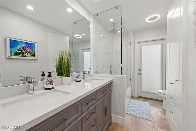 full bath with double vanity, recessed lighting, toilet, and a sink