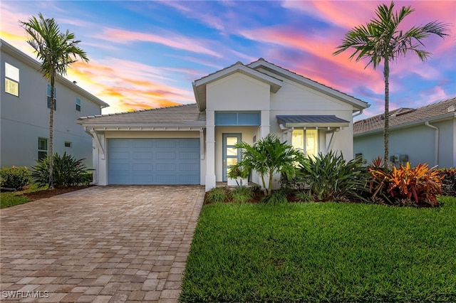 view of front facade featuring a tiled roof, decorative driveway, an attached garage, and stucco siding