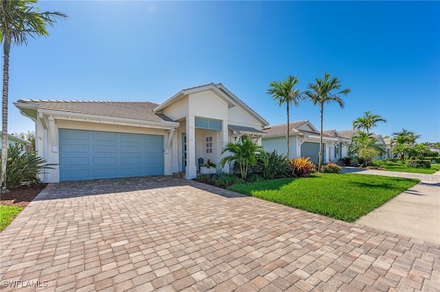 view of front of home featuring a tiled roof, a front yard, stucco siding, decorative driveway, and an attached garage