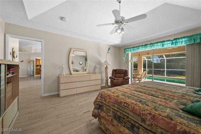 bedroom with a ceiling fan, baseboards, a tray ceiling, access to exterior, and light wood-style floors