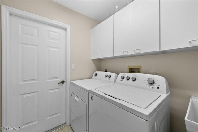 clothes washing area featuring a sink, cabinet space, and separate washer and dryer