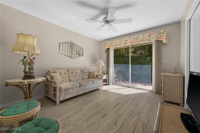 living area with ceiling fan, baseboards, radiator, and wood finished floors