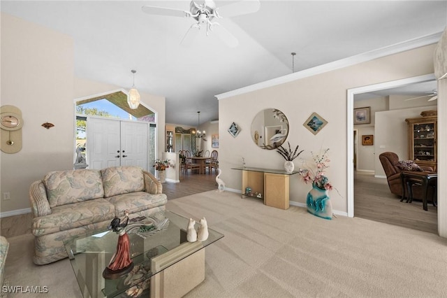 living room with vaulted ceiling, ceiling fan with notable chandelier, baseboards, and carpet floors