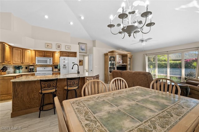 dining space featuring recessed lighting, light wood finished floors, high vaulted ceiling, and ceiling fan with notable chandelier