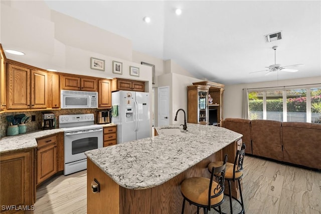 kitchen featuring white appliances, visible vents, a sink, decorative backsplash, and open floor plan