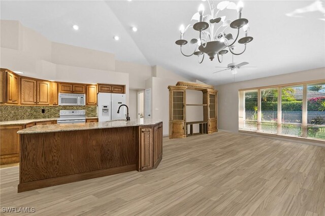 10164 Boca Ct, Naples, FL 34109 - kitchen with white appliances, brown cabinetry, a chandelier, light wood-type flooring, and high vaulted ceiling