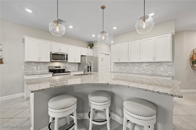 kitchen with a breakfast bar area, light tile patterned floors, a sink, appliances with stainless steel finishes, and white cabinetry