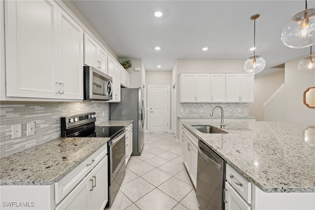 kitchen featuring a center island with sink, a sink, decorative light fixtures, appliances with stainless steel finishes, and white cabinets