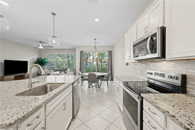 kitchen featuring light tile patterned floors, decorative backsplash, stainless steel appliances, white cabinetry, and a sink