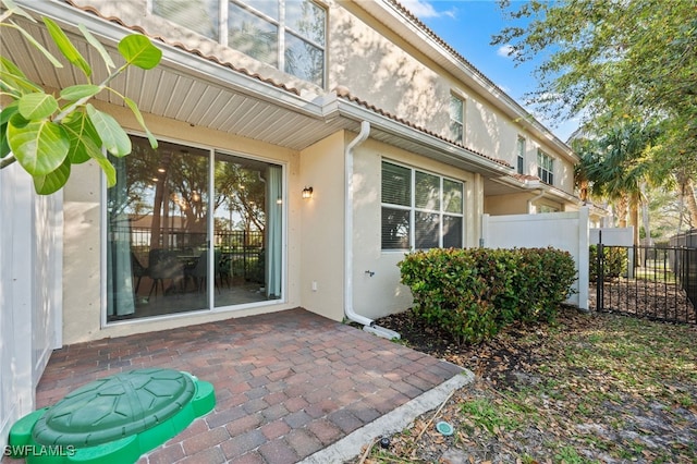 doorway to property with stucco siding, a patio area, and fence