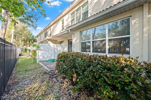 rear view of house with stucco siding and fence private yard