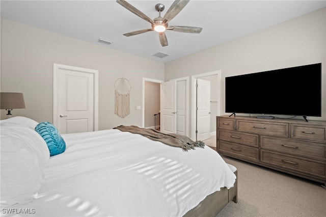 bedroom with visible vents, light colored carpet, and a ceiling fan