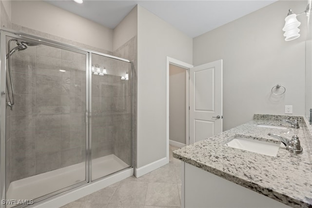 full bath with tile patterned floors, a shower stall, double vanity, and a sink