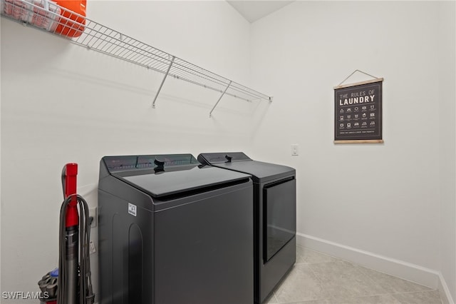 laundry room with laundry area, light tile patterned flooring, baseboards, and washer and clothes dryer