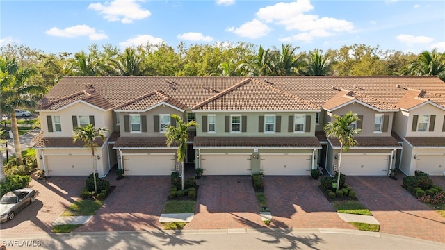 multi unit property with a tiled roof, an attached garage, and decorative driveway