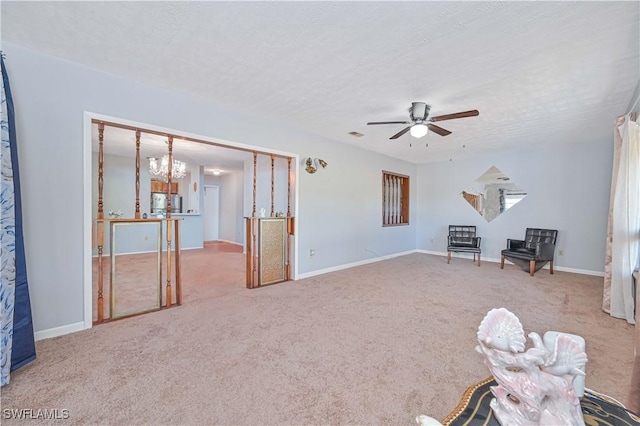 unfurnished room with carpet, ceiling fan with notable chandelier, baseboards, and a textured ceiling