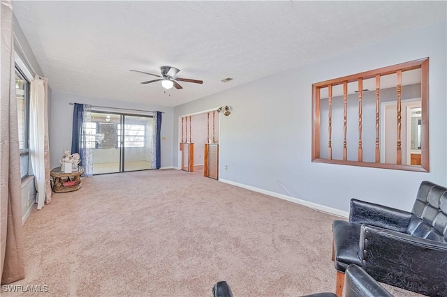 living area featuring baseboards, carpet floors, visible vents, and a ceiling fan