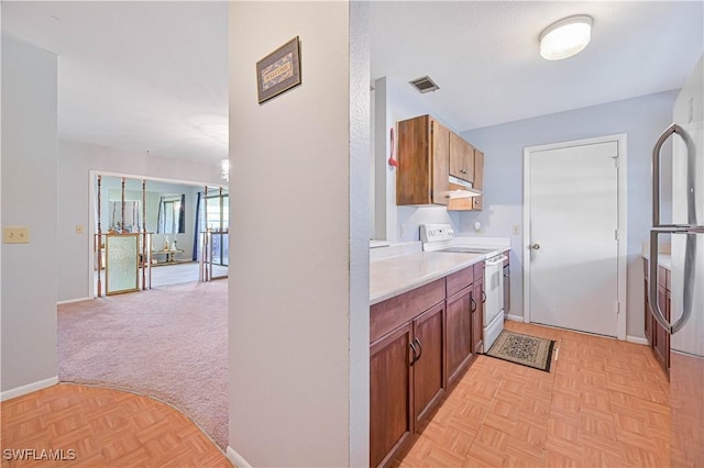 kitchen featuring visible vents, baseboards, white range with electric cooktop, light countertops, and brown cabinetry