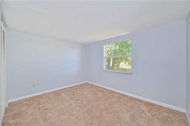 carpeted empty room featuring baseboards