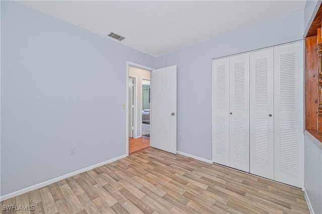 unfurnished bedroom with a closet, visible vents, light wood-style flooring, and baseboards