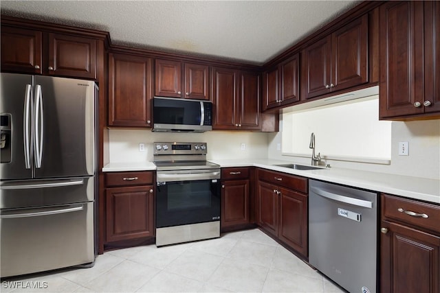 kitchen featuring a sink, stainless steel appliances, a textured ceiling, and light countertops