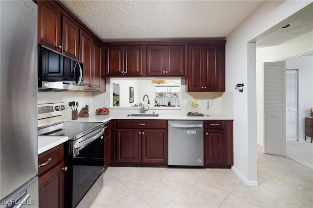 kitchen featuring a sink, a textured ceiling, appliances with stainless steel finishes, light countertops, and light tile patterned floors