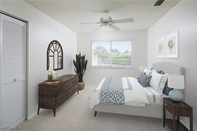 carpeted bedroom featuring baseboards, visible vents, ceiling fan, a closet, and a textured ceiling